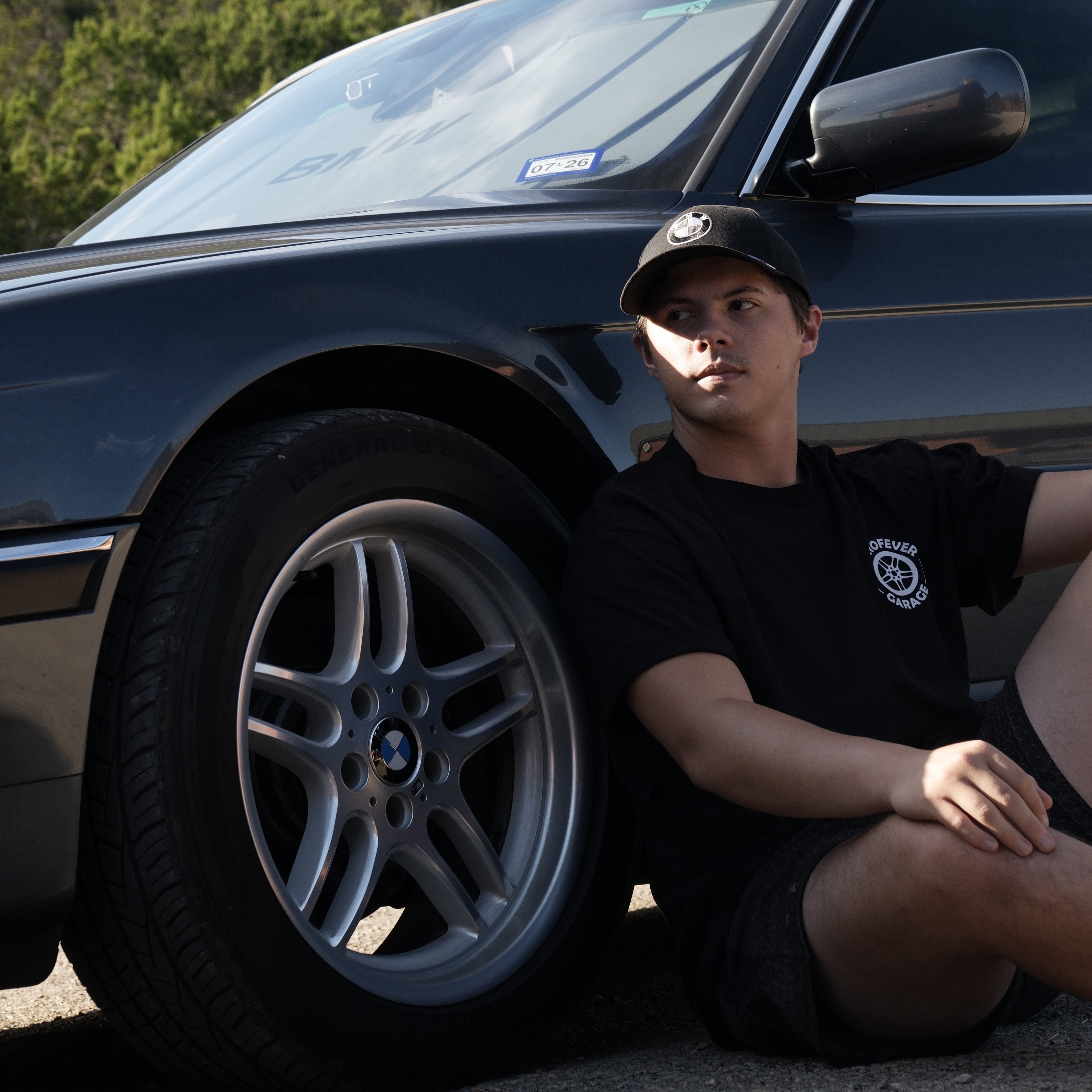 Donovan, the owner of Eurofever Detailing, leans against his 2000 BMW E38 for a portrait photo.
